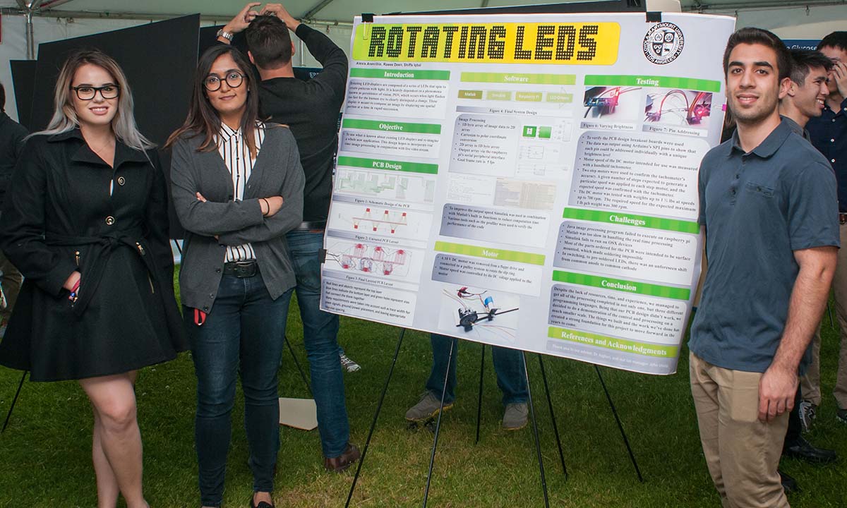 Two female students and male student standing in front of research poster